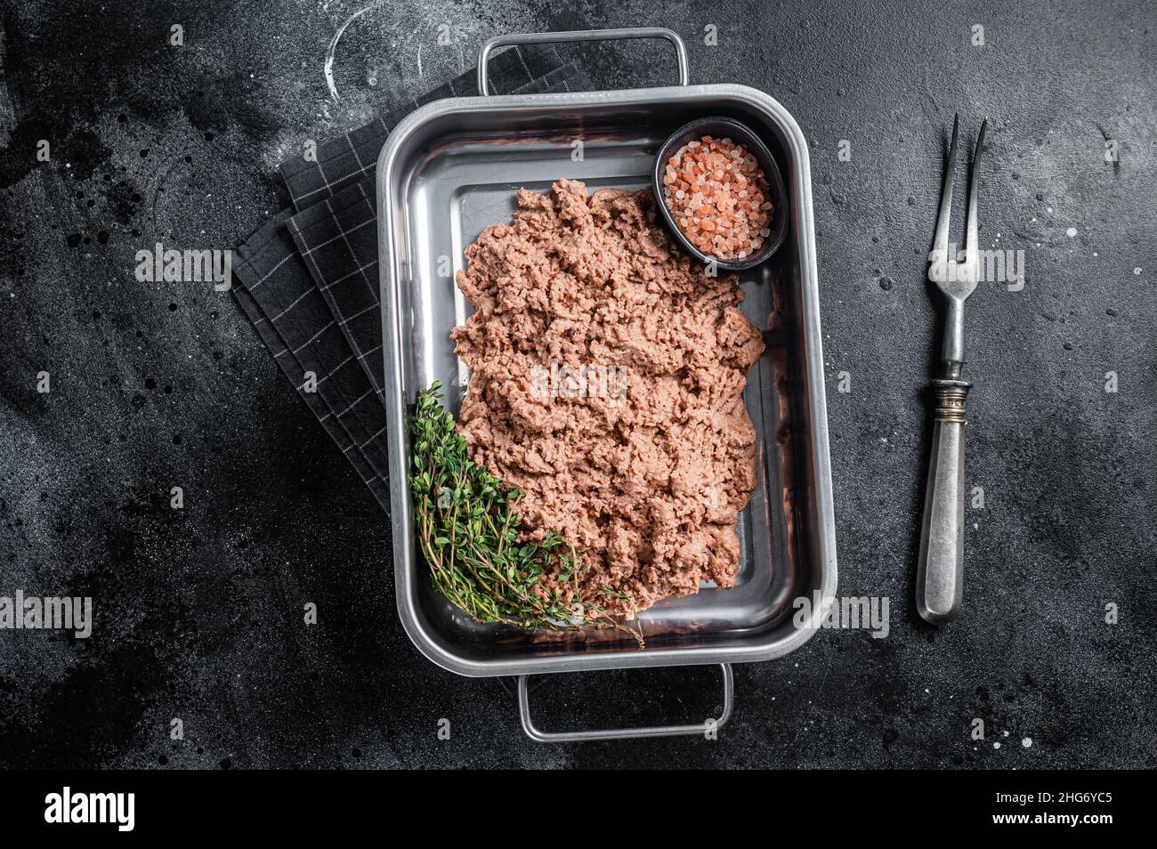 Carne vegetariana macinata, carne cruda a base di piante con erbe in cucina vassoio sfondo nero. Vista dall'alto Foto Stock
