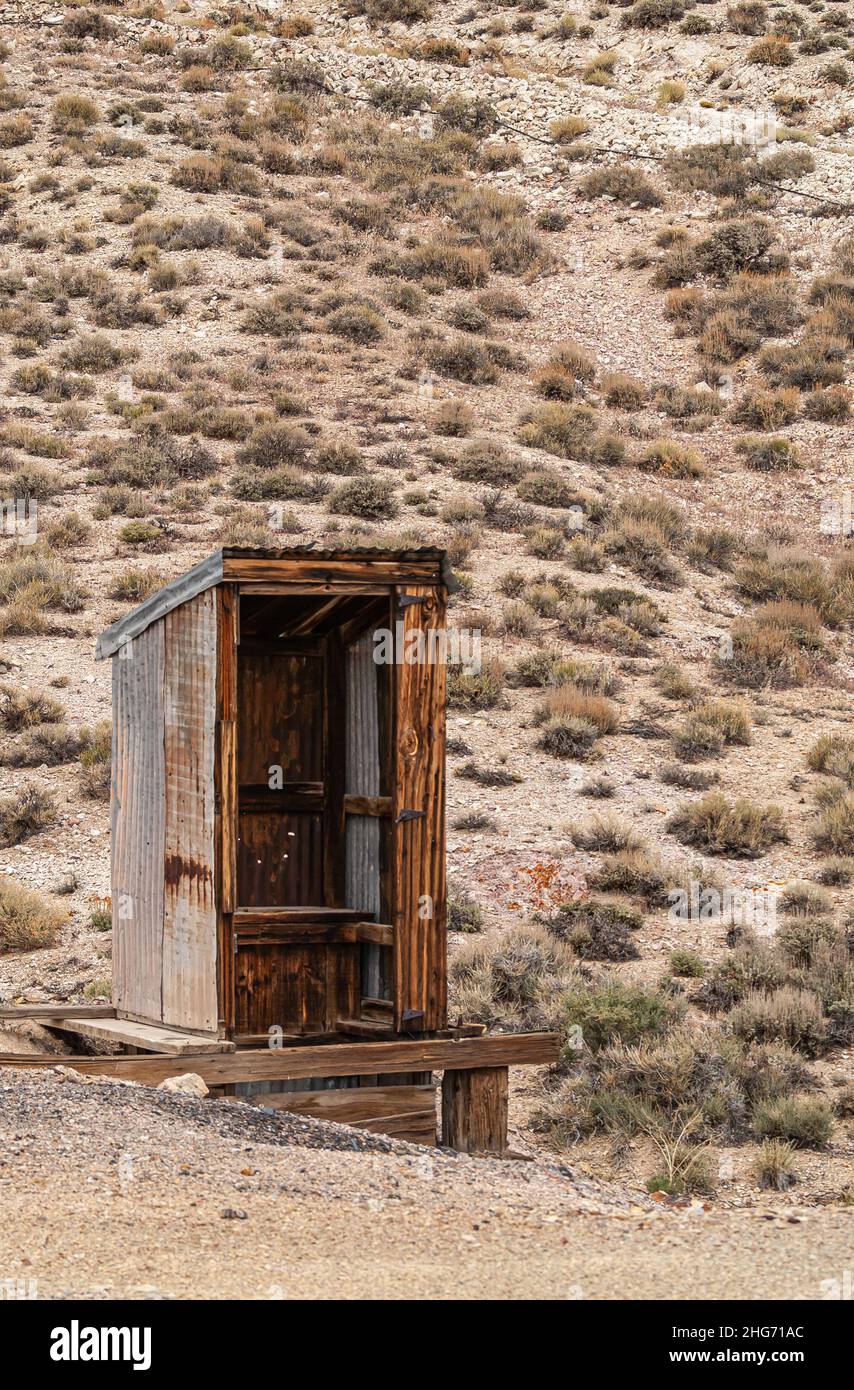 Tonopah, Nevada, USA - 19 maggio 2011: Primo piano di gabinetto in legno marrone aperto posto sul pavimento del deserto beige secco nella miniera abbandonata. Foto Stock