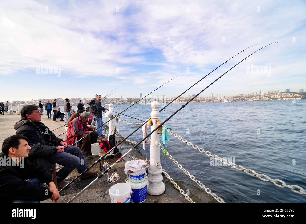 Uomini turchi che pescano dal lungomare della Uskudar Coast Walkway lungo lo stretto del Bosforo nel lato asiatico di Istanbul, Turchia. Foto Stock