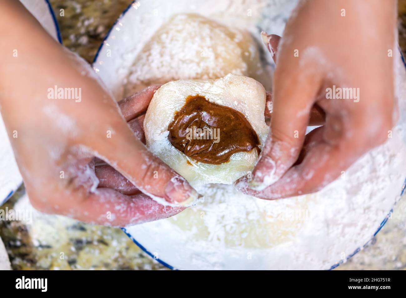 Vista dall'alto piatta delle mani che modellano la cottura facendo la torta di riso giapponese mochi appiccicosa daifuku con ripieno di cioccolato e farina di amido come dessert tradizionale Foto Stock