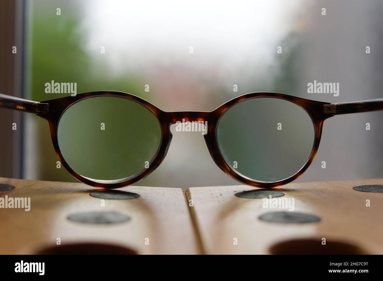 Guardando attraverso gli occhiali su un tavolo con sfondo sfocato della luce della finestra Foto Stock