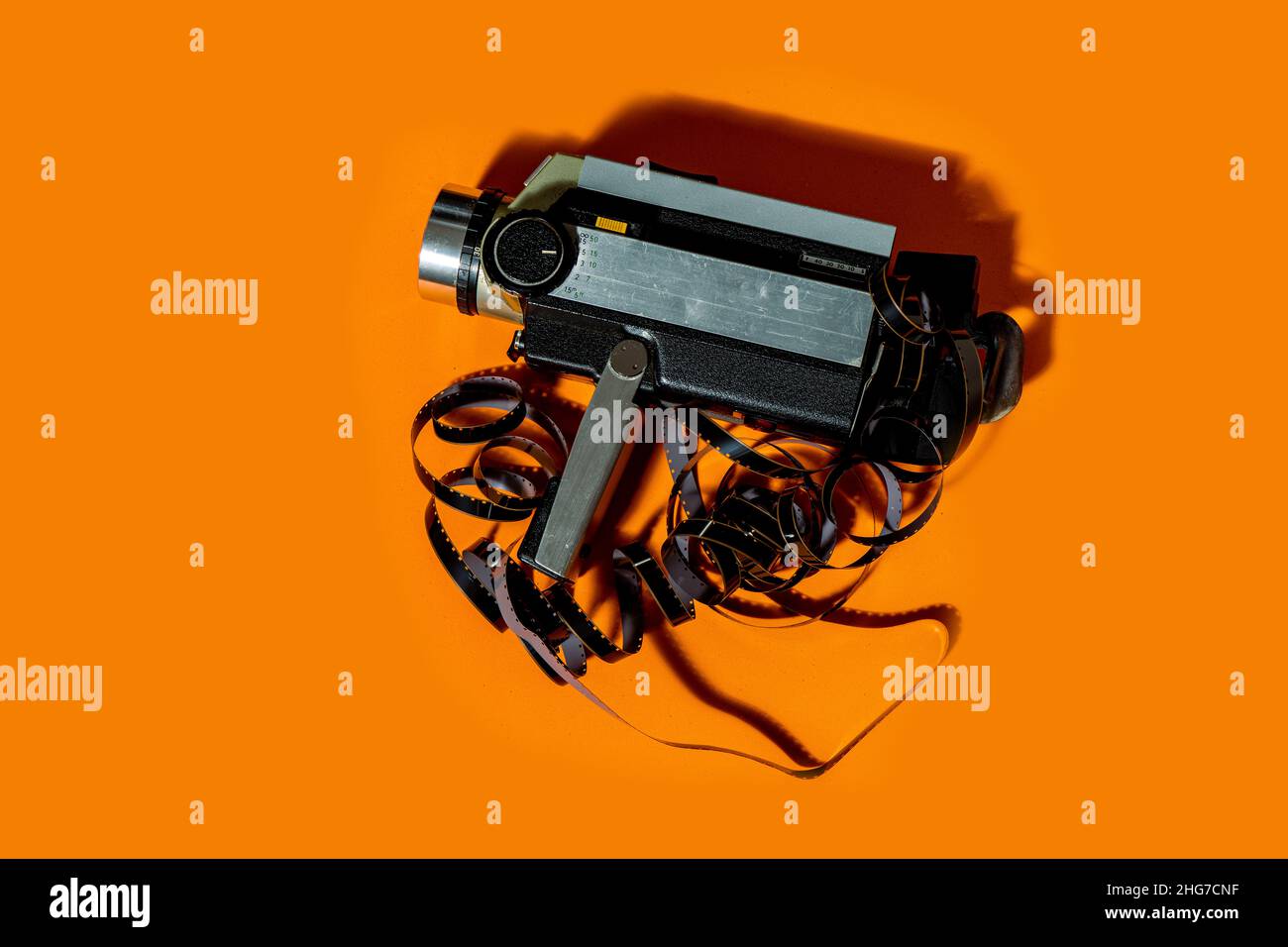 Un vecchio camcorder vintage con il film negativo sfocato su sfondo arancione. Foto Stock