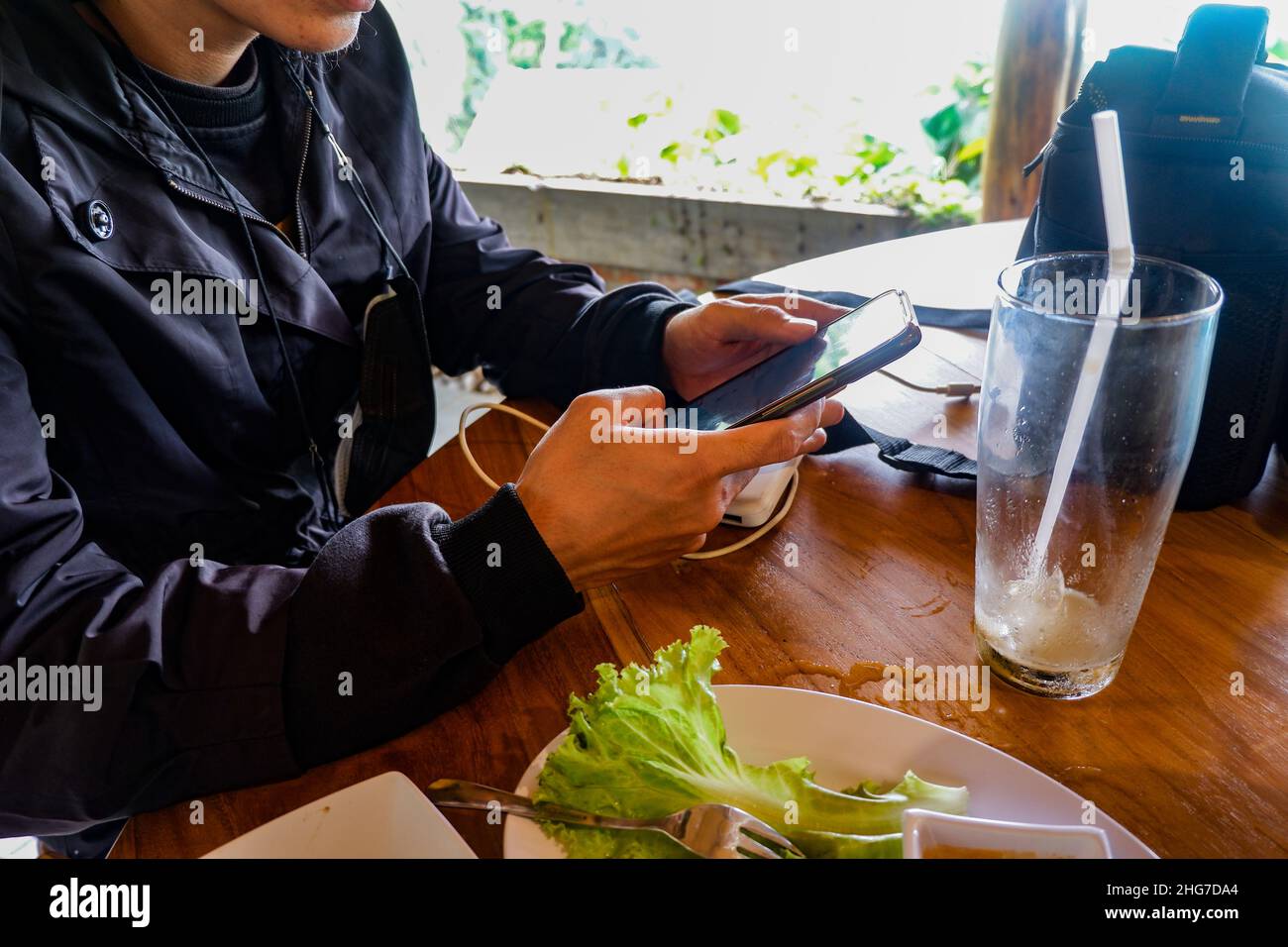 l'uomo d'affari del ristorante usa un cellulare, indossava una giacca nera, foto scattata a mezzogiorno Foto Stock