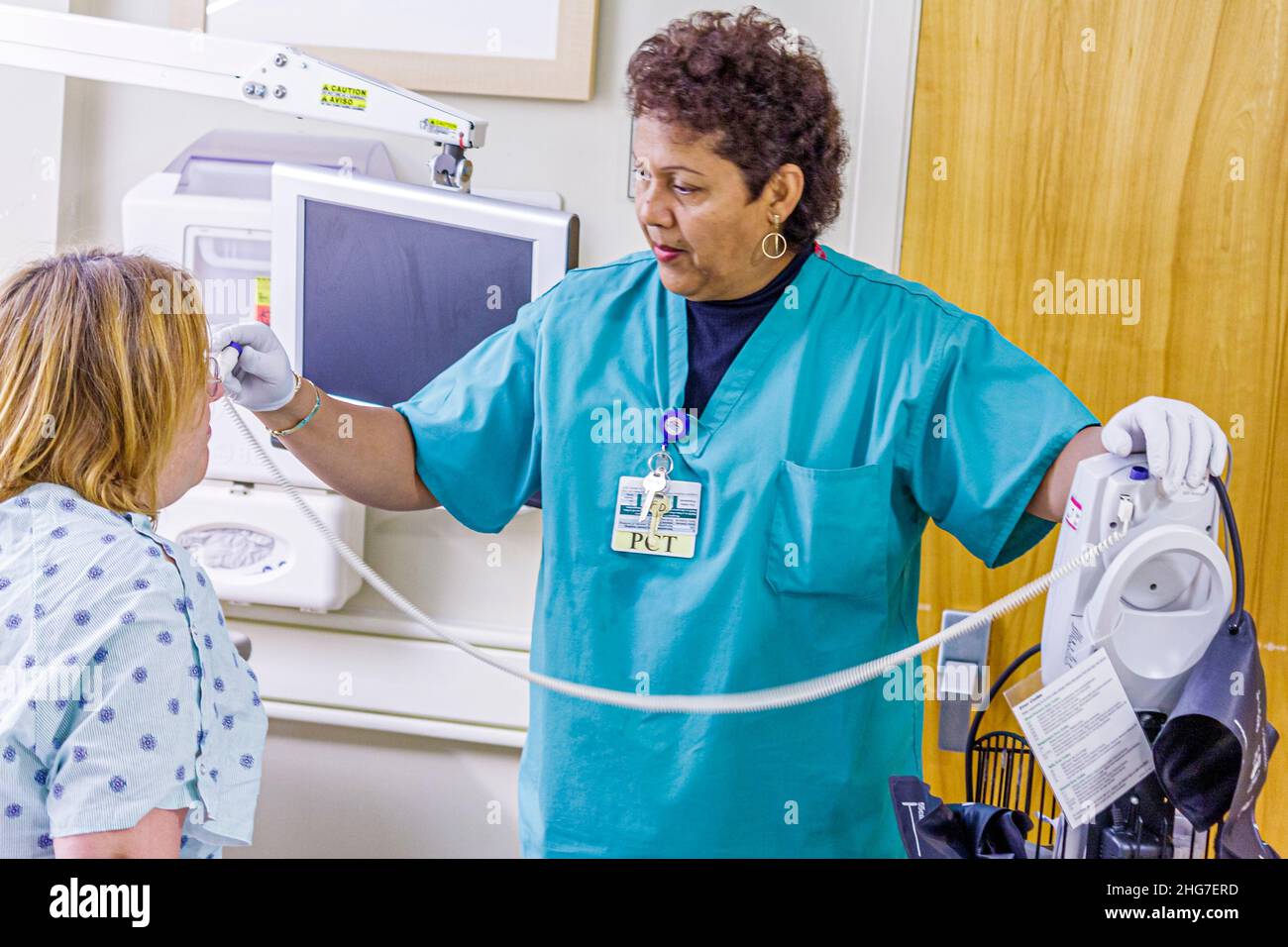 Florida University of Miami Doctor's Hospital, ispanica donna nera che prende temperatura stanza esame paziente termometro personale sanitario infermiere medico Foto Stock