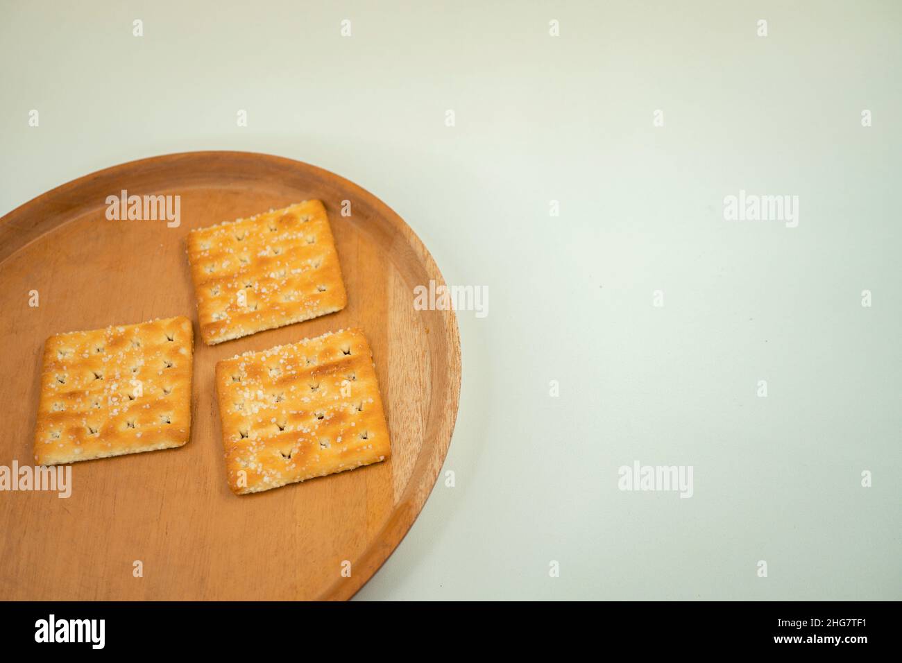 primo piano foto cracker biscotto sopra il piatto di legno, forchetta e cucchiaio, con fondo bianco macinato. Che le foto sono perfette per il cibo opuscolo. Foto Stock