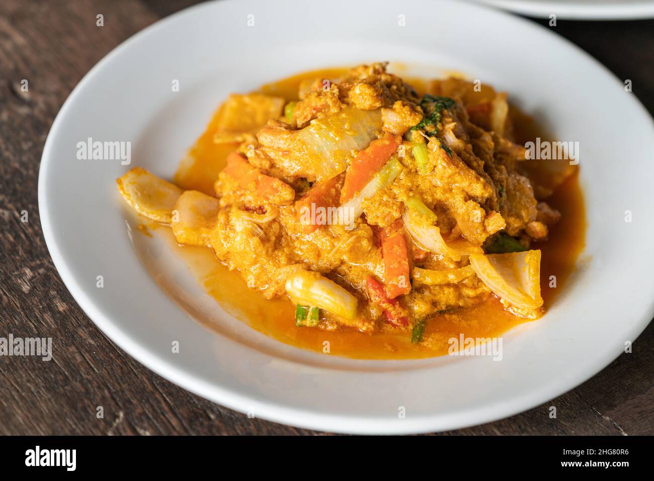 Primo piano su crabmeat fritto con curry in polvere e uova, frutti di mare sani cibo tailandese su tavola di legno, luce naturale. Foto Stock