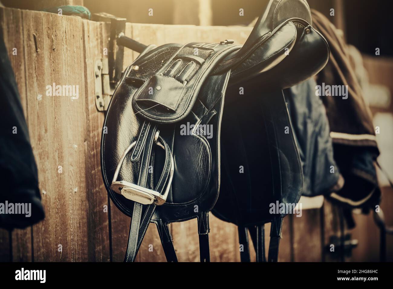 Selle marroni e nere appendono alla stalla. Munizioni di cavallo. Sport equestre. Foto Stock