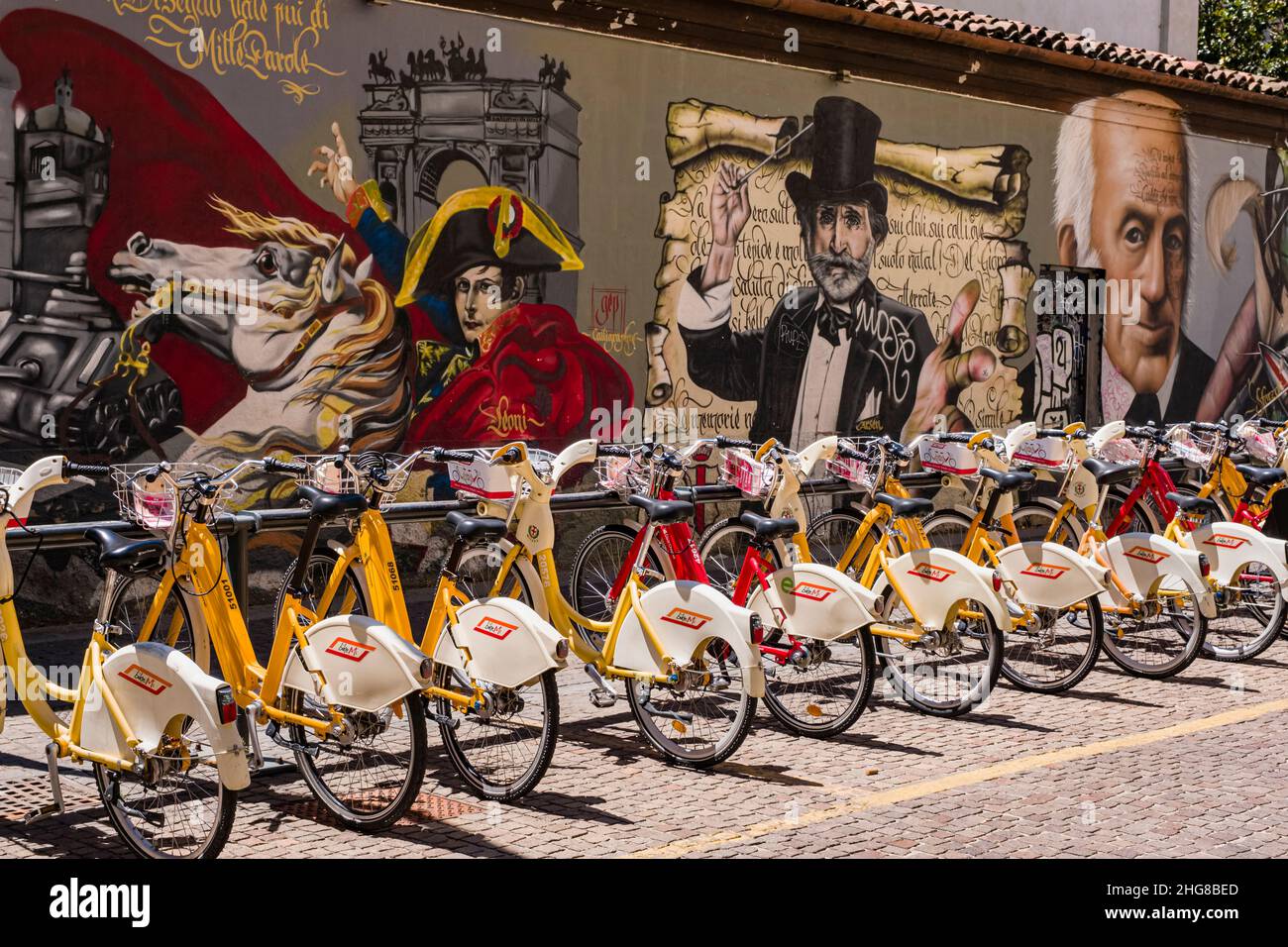 Noleggio biciclette allineate di fronte a una parete di colorati graffiti fantasiosi con temi storici. Foto Stock Noleggio biciclette allineate di fronte a una parete di colorati graffiti fantasiosi con temi storici. Foto Stock