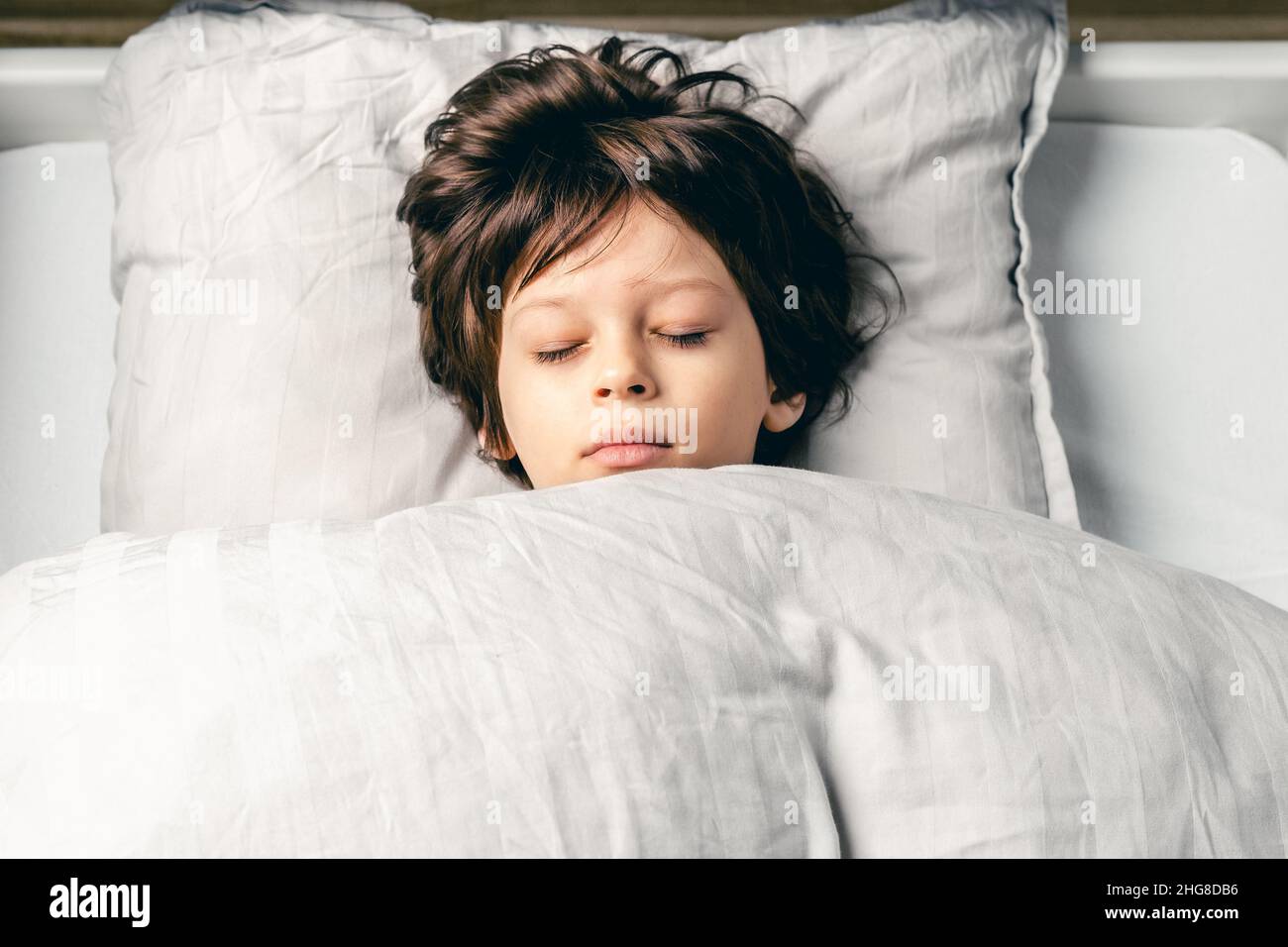 Ragazzo carino europeo che dorme tranquillamente nel letto di casa, buon tempo di dormire Foto Stock