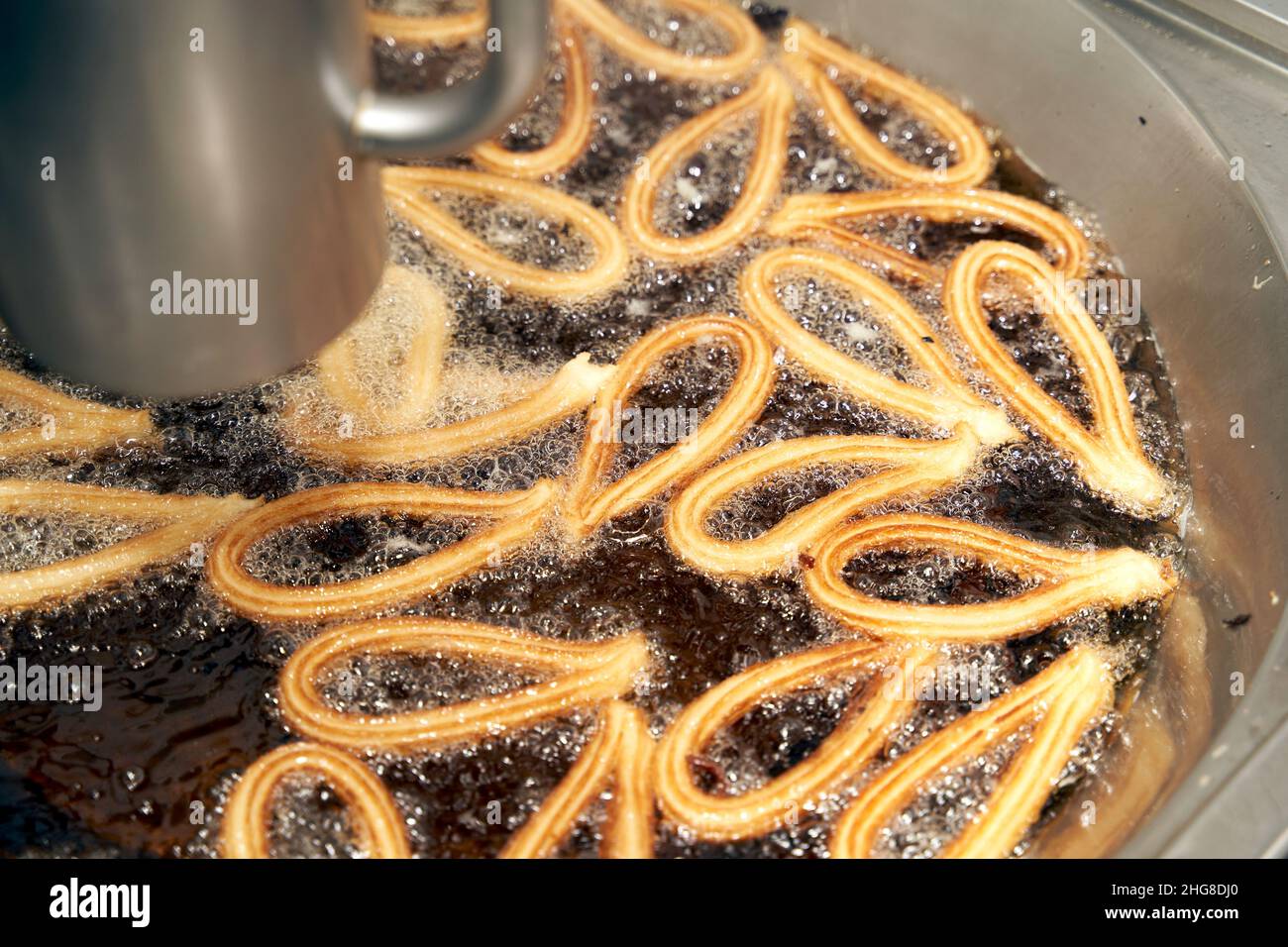 Cottura della pasta Churro in olio bollente. Tipica colazione spagnola Foto Stock