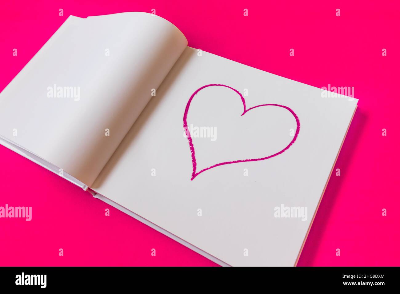 Disegnata a cuore in un notebook su sfondo rosa. Buon San Valentino. Foto Stock