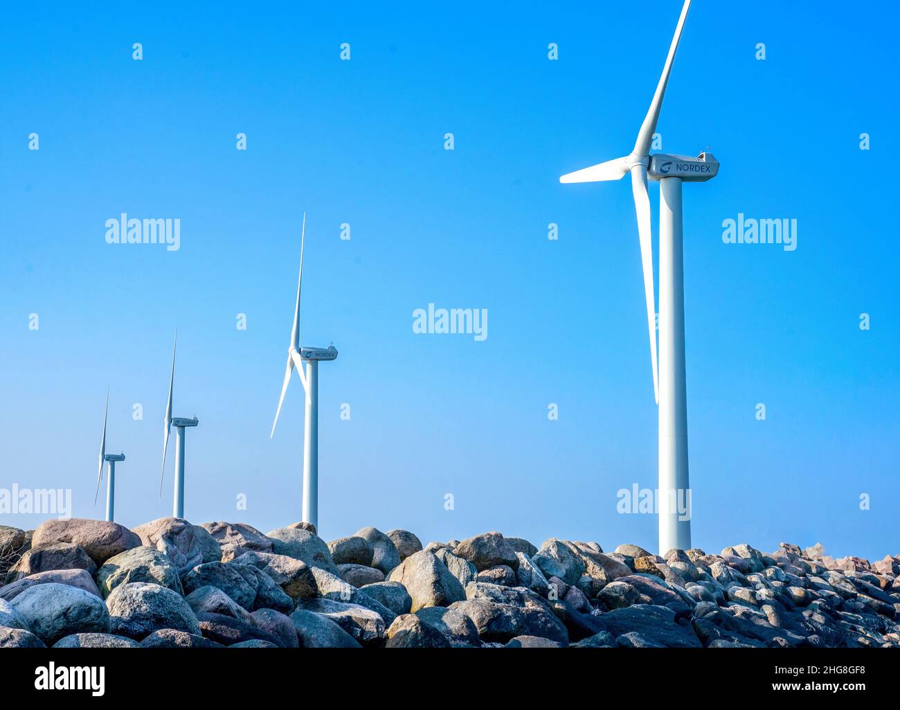 Turbine eoliche che ruotano graziosamente contro un cielo blu vibrante in Danimarca, mostrando energia rinnovabile e sostenibilità in un paesaggio pittoresco. Foto Stock