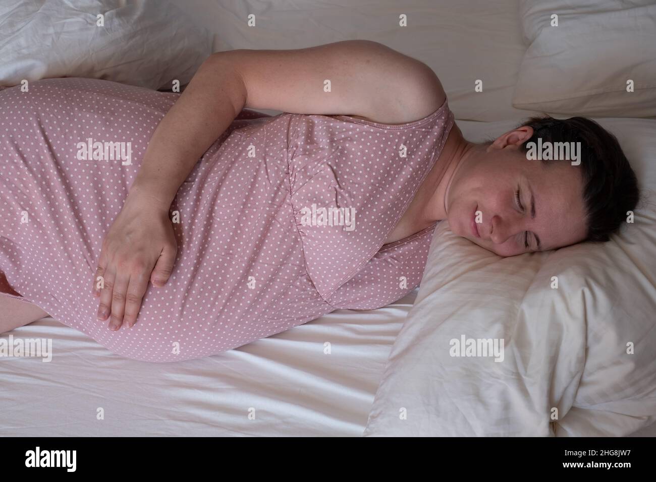Donna incinta dorme tranquillamente in camera da letto Foto Stock