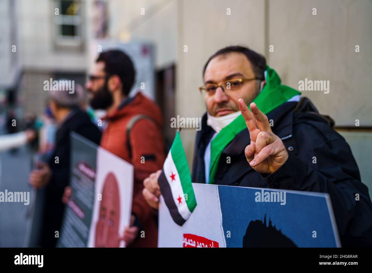 19 gennaio 2022, Hessen, Francoforte sul meno: Un attivista siriano fa il 'segno della Vittoria' davanti al tribunale. Un altro processo per crimini contro l'umanità nel paese di guerra civile della Siria inizia mercoledì alla Corte Regionale superiore. L'imputato è un medico di 36 anni. Il procedimento penale federale lo accusa di tortura e di uccisione premeditata di un prigioniero. Nel 2011 e nel 2012, avrebbe inflitto gravi danni fisici e mentali ai prigionieri in un ospedale militare e in una prigione militare di intelligence a Homs. Foto: Andreas Arnold/dpa Foto Stock