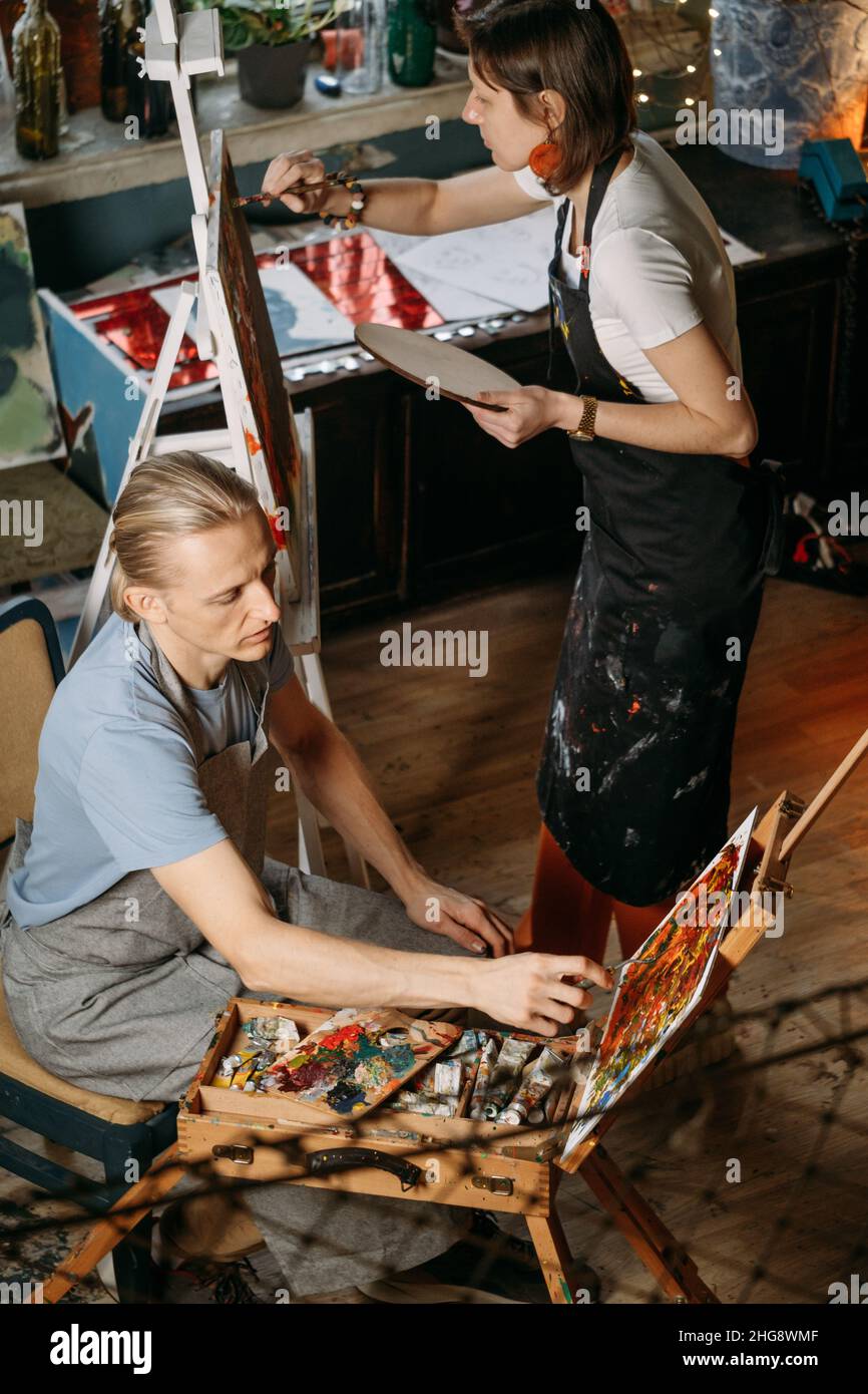 Gruppo creativo laboratorio di pittura su tela grande in studio. Studenti di pittura a lezioni d'arte. Educazione artistica per adulti. Hobby e lavoro Foto Stock