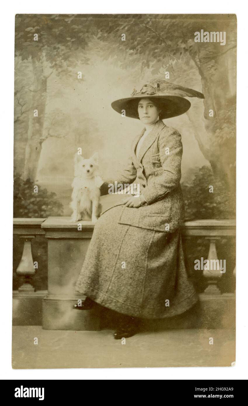 Originale Titanic / tardo Edwardian era ritratto cartolina di attraente signora in grande cappello indossando una giacca alla moda e gonna, con cane terrier, risale a circa 1911 studio di Woodwards, Guernsey. Foto Stock