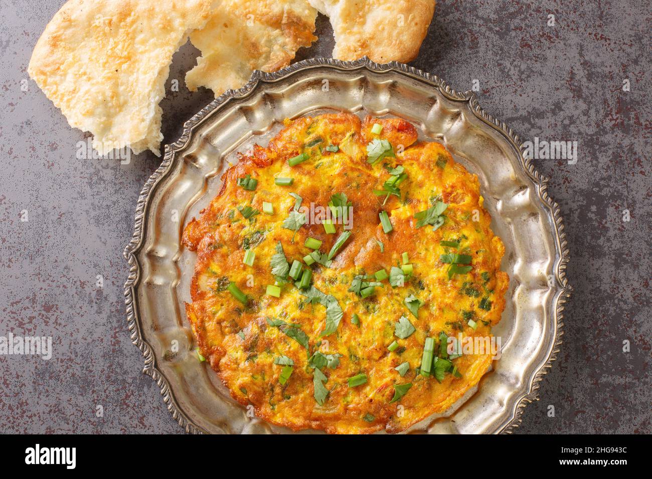 Vista ravvicinata di omelette di masala indiana piccante sul piatto sul tavolo. Vista dall'alto orizzontale Foto Stock