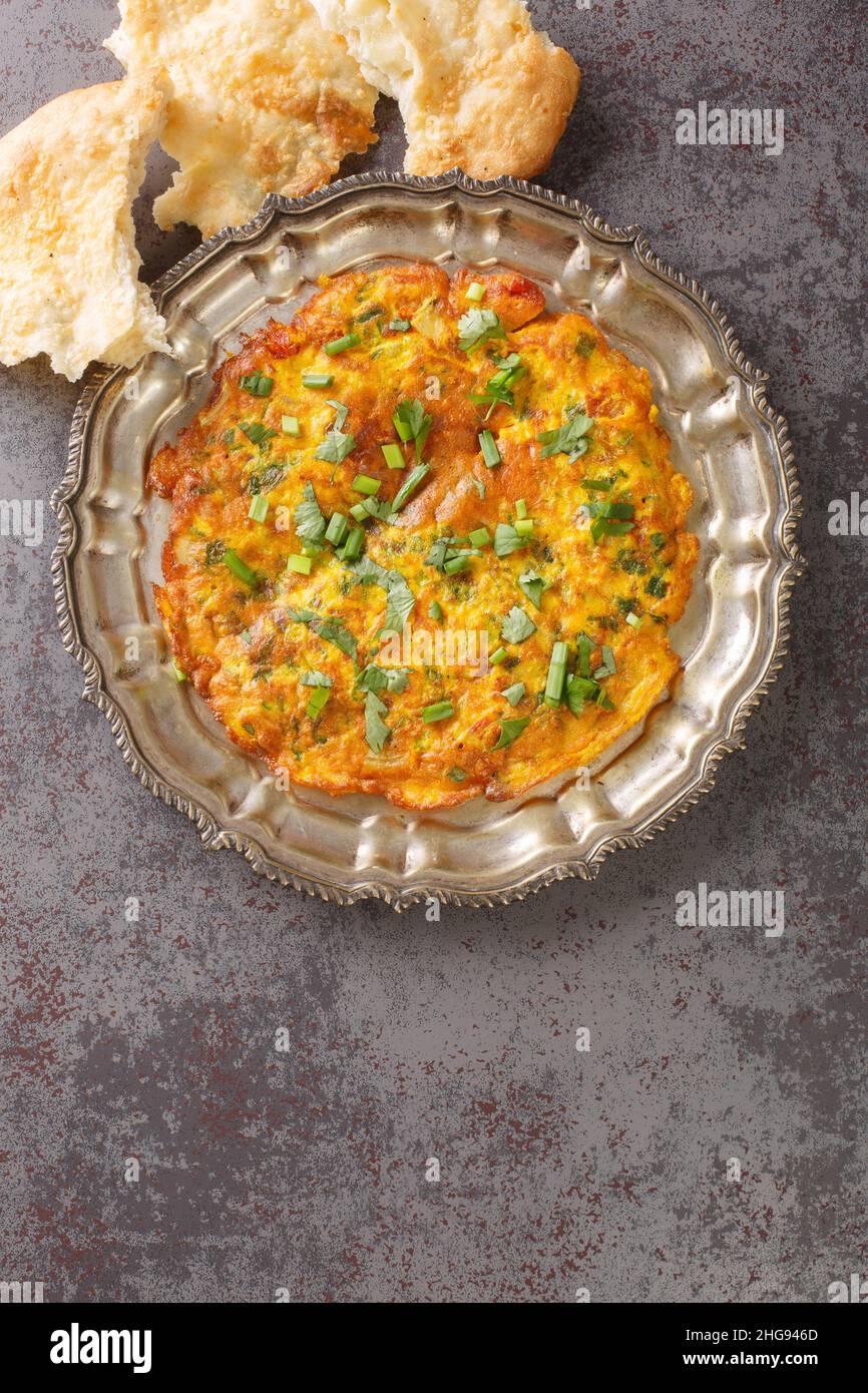 Ricette indiane Masala Omelet con verdure fresche in primo piano nel piatto sul tavolo. Vista dall'alto verticale Foto Stock