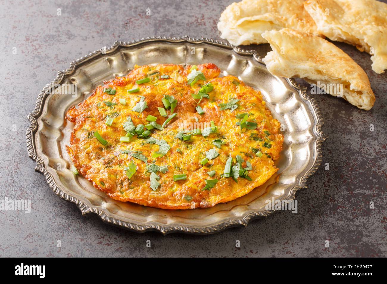 Popolare ricetta indiana nepalese Masala Omelet servita sul piatto sul tavolo. Orizzontale Foto Stock
