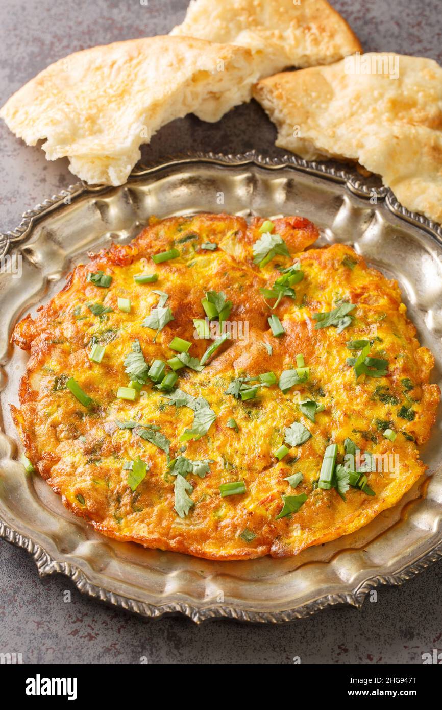 Masala Omelet in stile indiano famoso cibo di strada di Mumbai primo piano nel piatto sul tavolo. Verticale Foto Stock