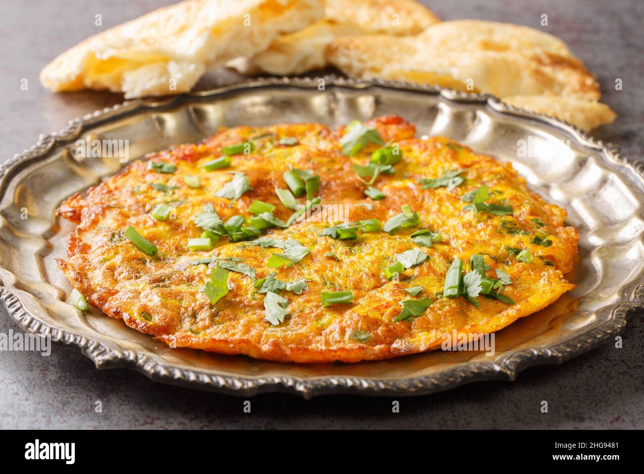 Vista ravvicinata di omelette di masala indiana piccante sul piatto sul tavolo. Orizzontale Foto Stock