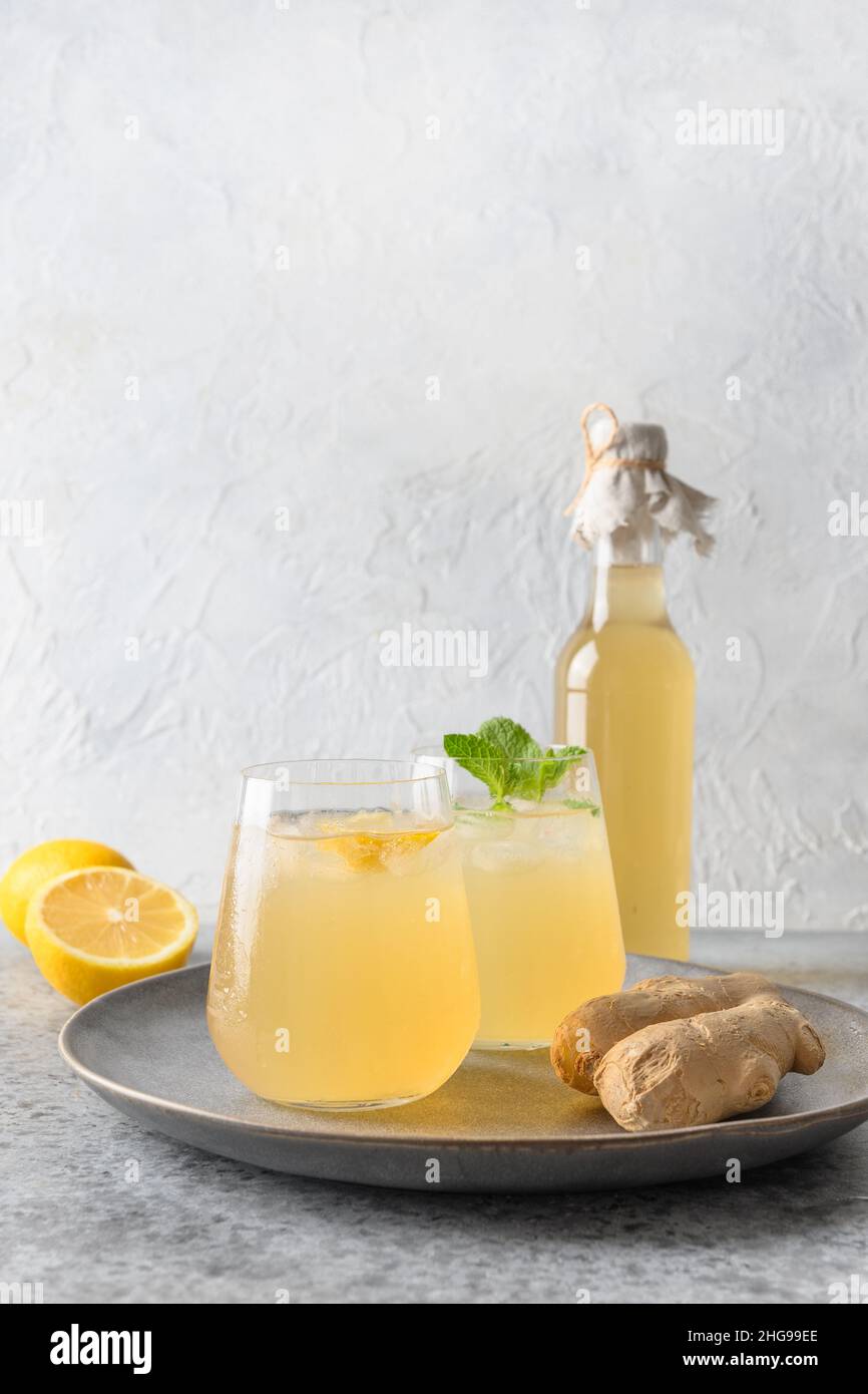 Gustoso Kombucha in bicchiere e bottiglia con limone e zenzero. Bevanda probiotica organica heathy. Formato verticale. Primo piano. Foto Stock