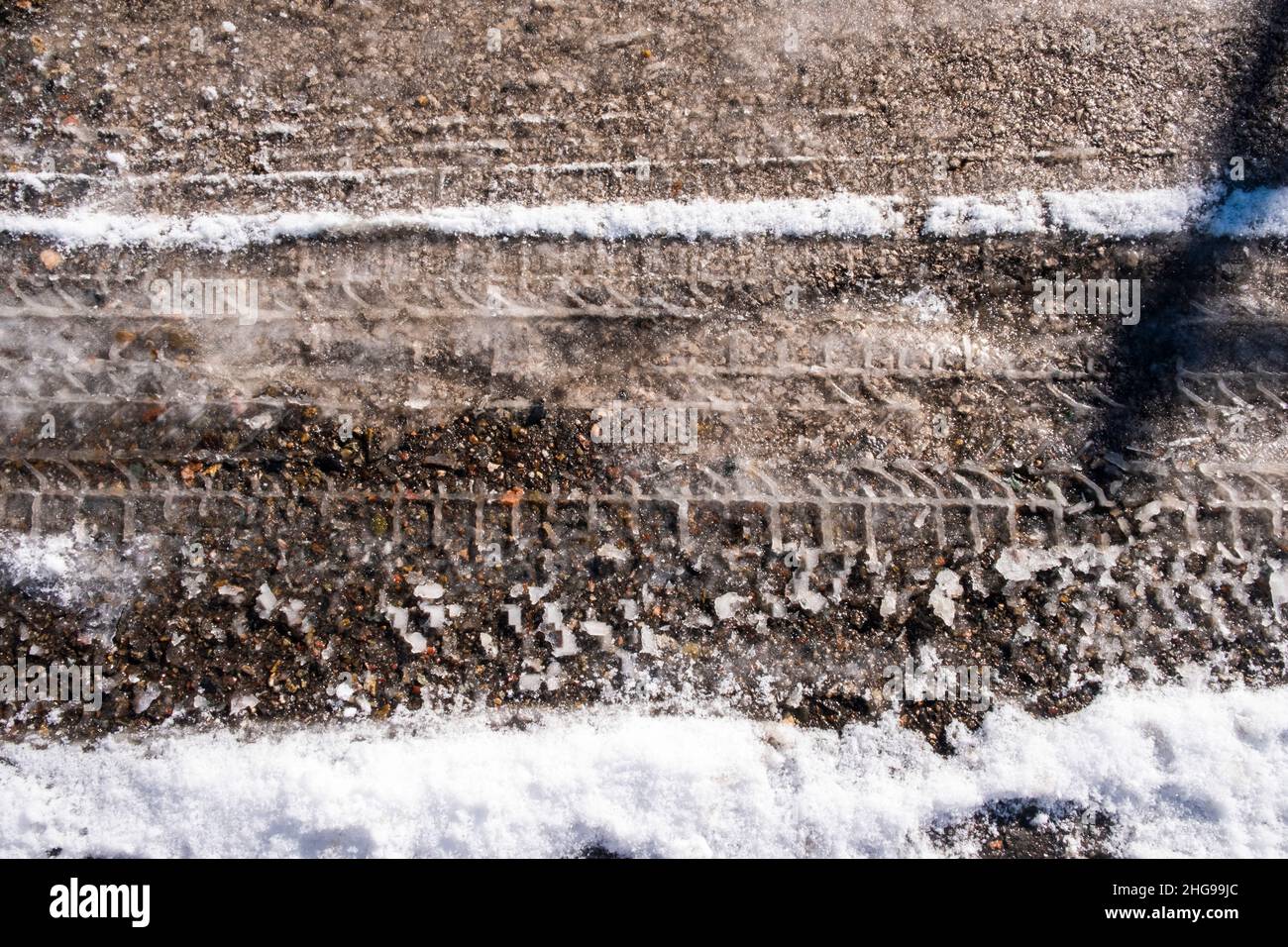 le piste degli pneumatici sulla neve fondente sull'asfalto. Foto Stock