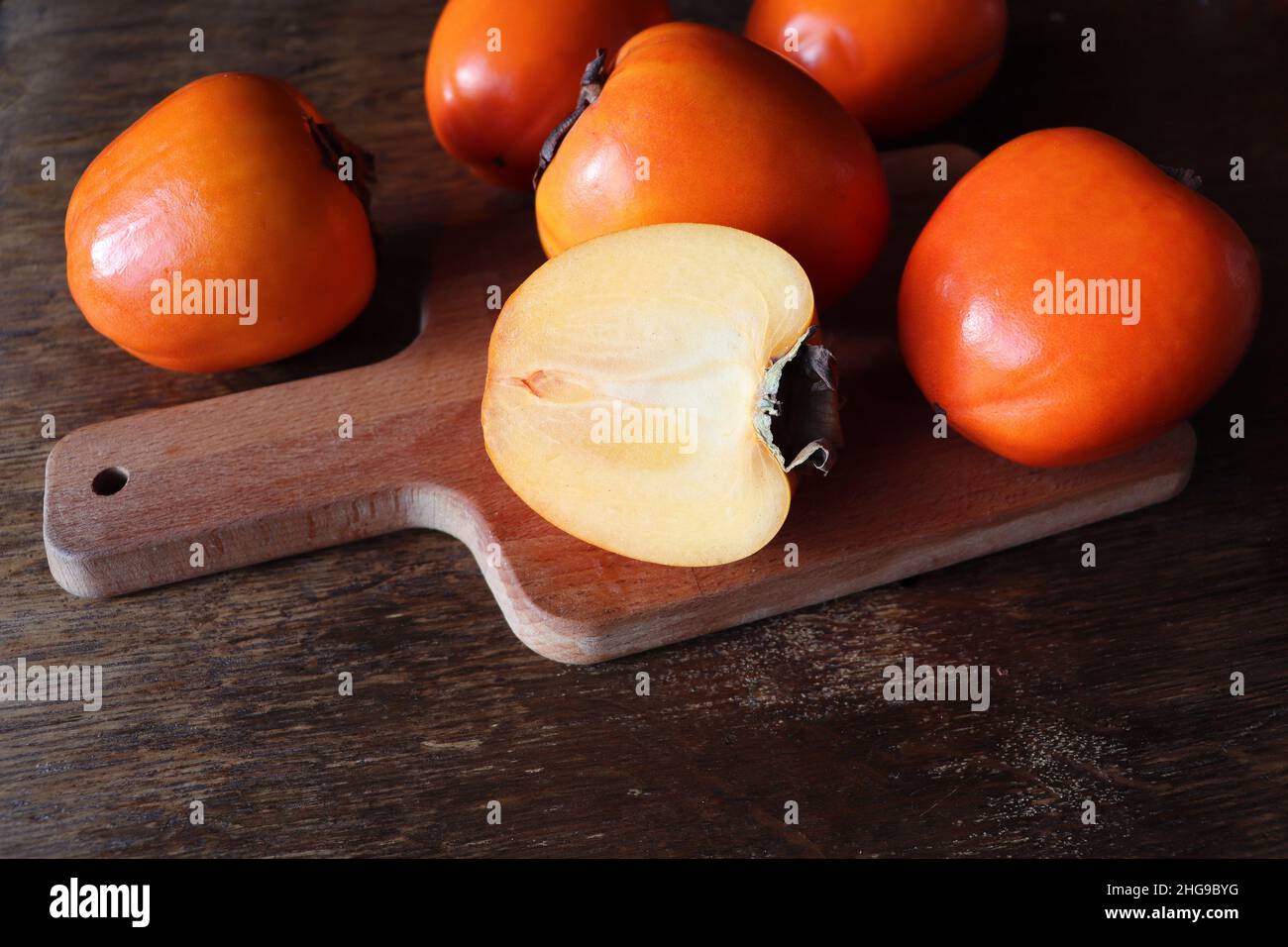 Frutta fresca biologica matura Persimmons con fetta su vecchio sfondo tavolo di legno. Vista dall'alto. Disposizione piatta. Spazio di copia per testo e contenuto. Foto Stock