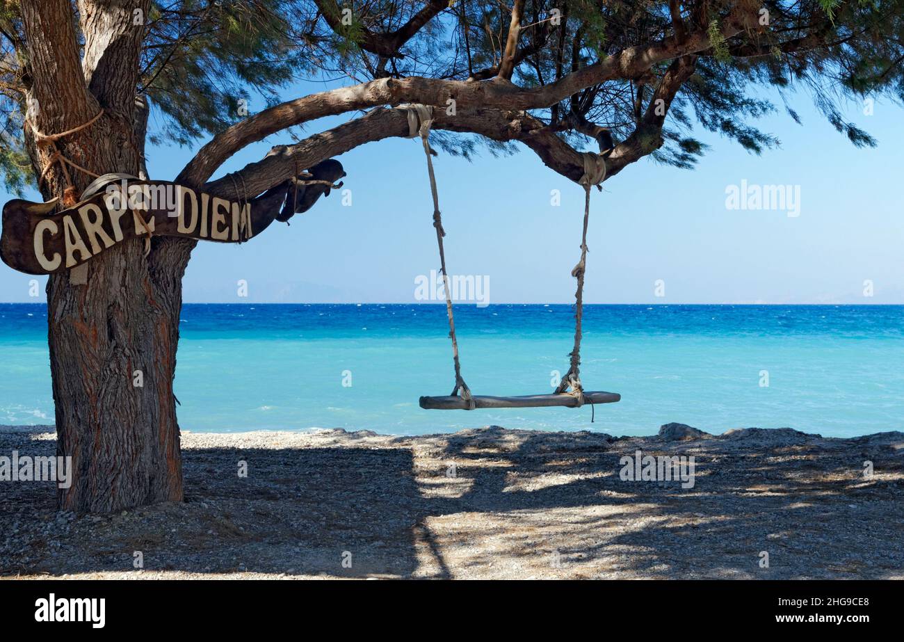 Altalena e albero con cartello Carpe Diem, Tilos, Isole Dodecanesi, Grecia. Foto Stock