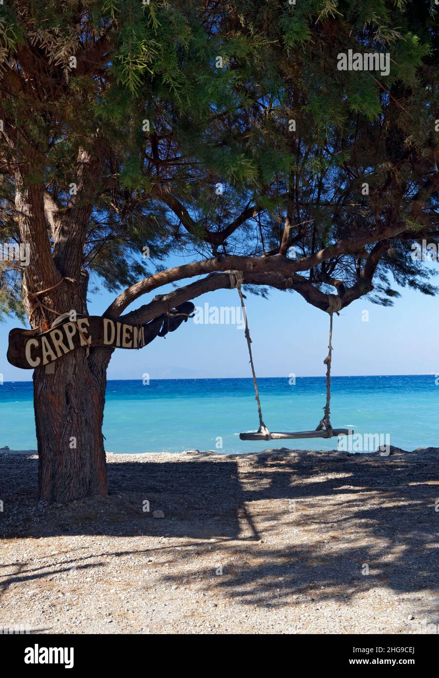 Altalena e albero con cartello Carpe Diem, Tilos, Isole Dodecanesi, Grecia. Foto Stock