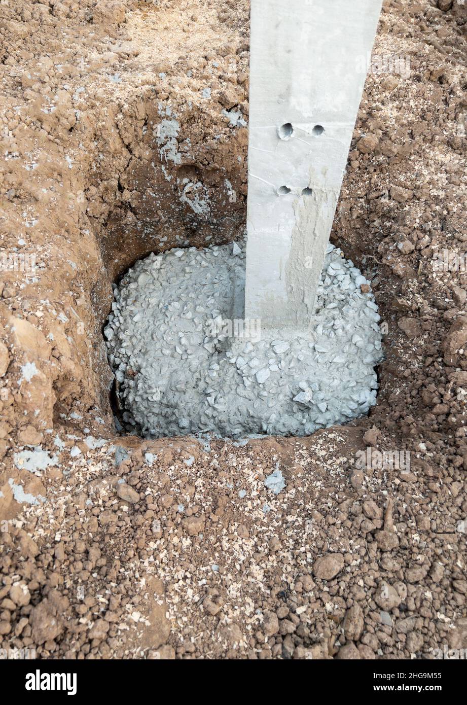 Il cemento mescolato con le pietre nei fori di pilastro di calcestruzzo per la costruzione del garage della casa di campagna, vista frontale con lo spazio di copia. Foto Stock