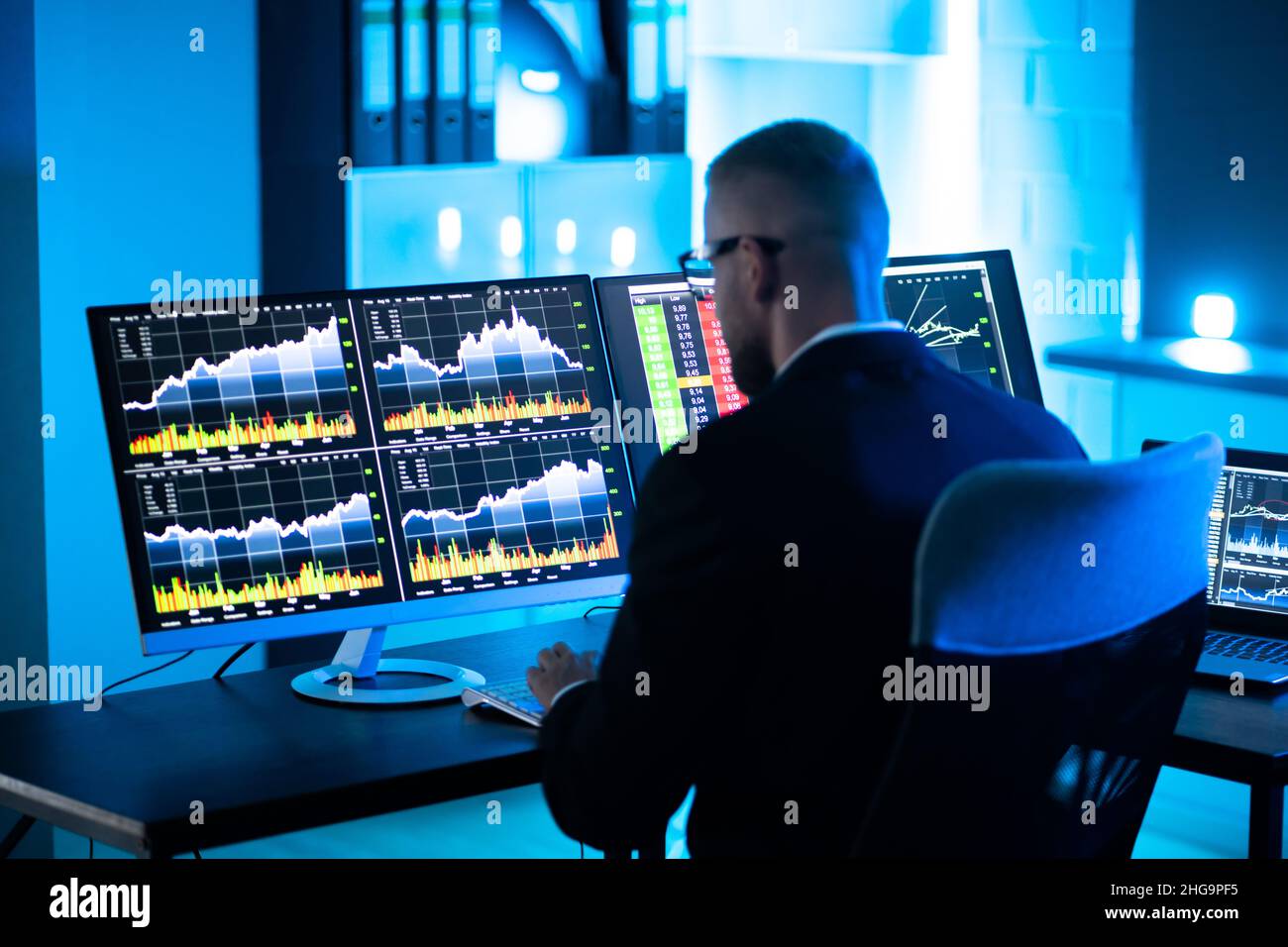 L'uomo commerciante di riserva usando i monitor multipli del calcolatore Foto Stock