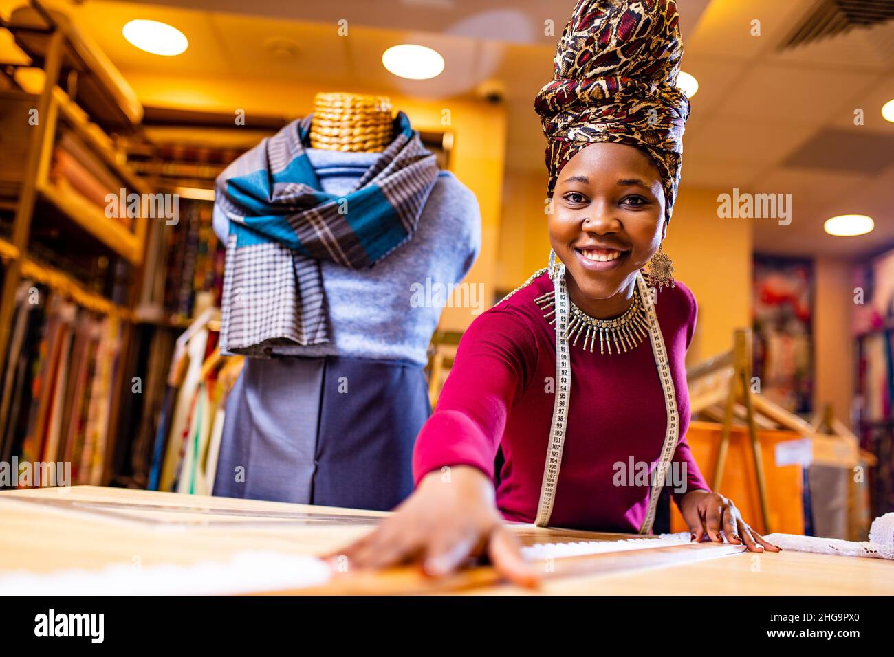 donna tanzaniana con serpente stampa turban oltre sentire lavorare in negozio di tessuti Foto Stock