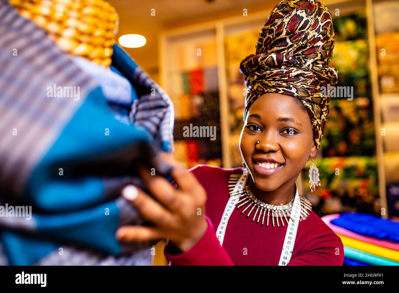 donna tanzaniana con serpente stampa turban oltre sentire lavorare in negozio di tessuti Foto Stock