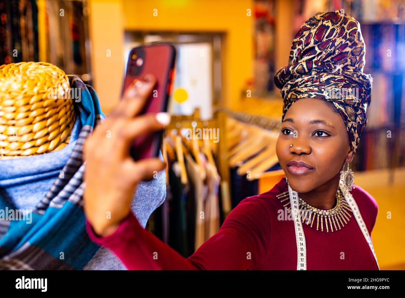 tanzanian donna con serpente stampa turban oltre sentire lavorare in tessuti negozio selfie presa su fotocamera telefono Foto Stock