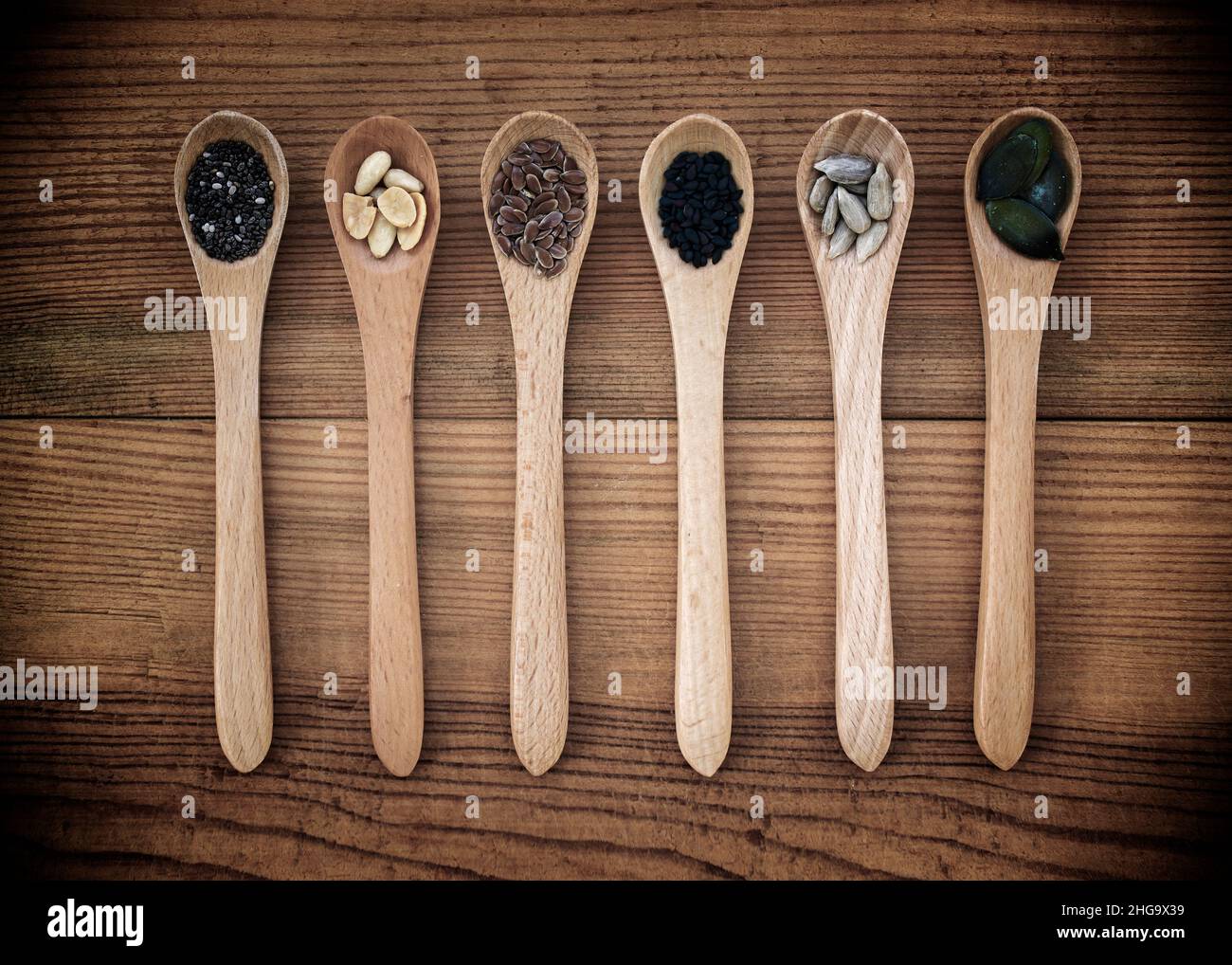 Set di semi organici in cucchiai su sfondo di legno, cibo naturale sano e concetto di nutrizione Foto Stock