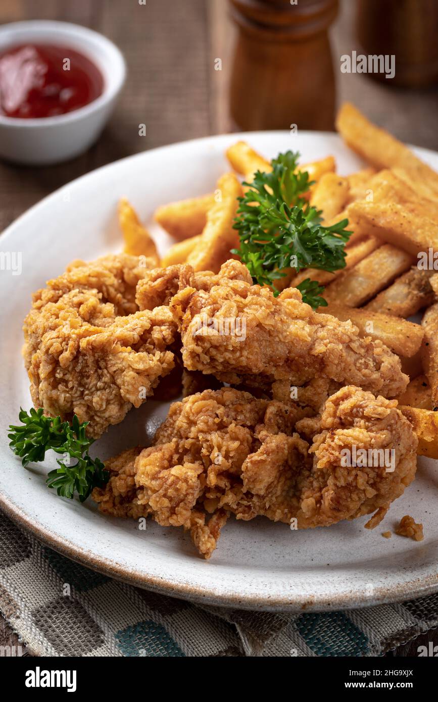Croccanti polli fritti e patatine fritte guarnite con prezzemolo su un piatto Foto Stock