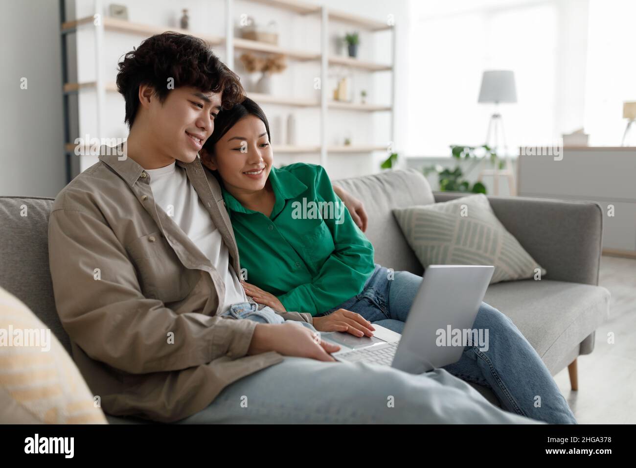 Concetto di passatempi per il fine settimana. Sposato giovane coppia asiatica usando il portatile a casa, rilassarsi sul divano insieme, spazio copia Foto Stock