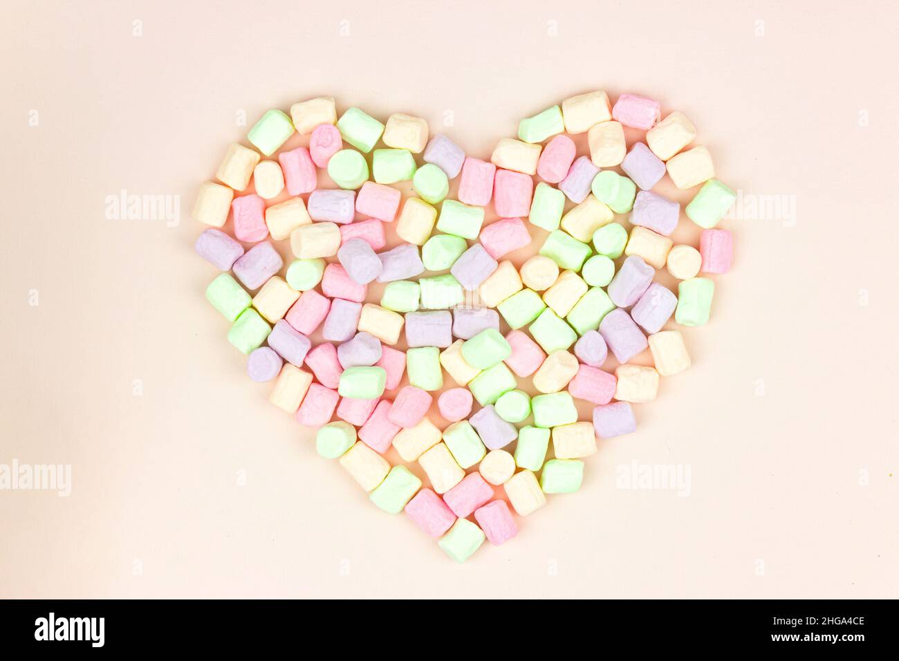 Pastello a forma di cuore multicolore marshmallow su sfondo rosa pastello. Sfondo alimentare. Concetto di festa e festa. Foto Stock