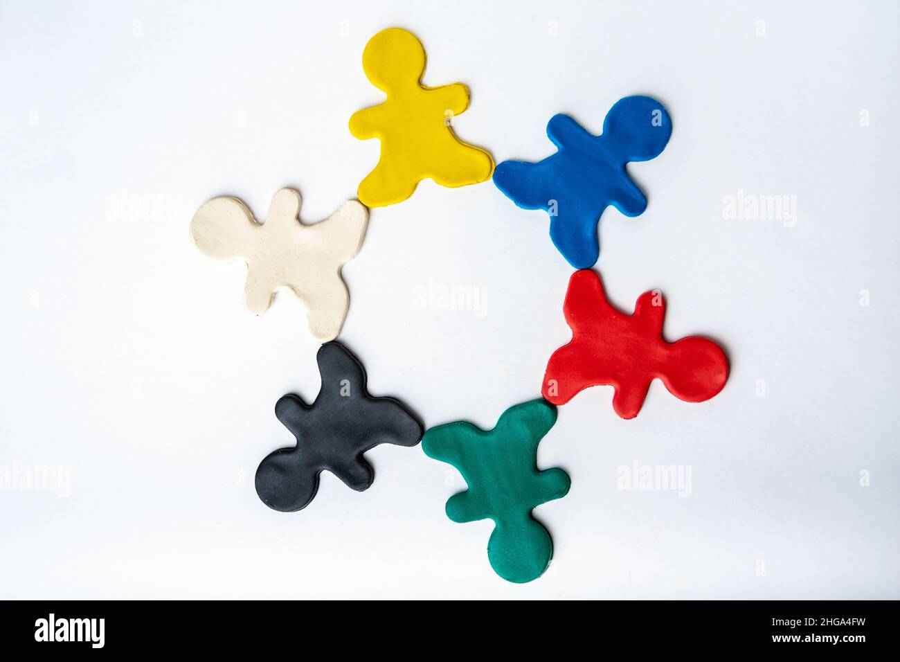 Multicolore uomini di argilla luminosa in un cerchio isolato su sfondo bianco, piatto, vista dall'alto. Il concetto di amicizia, i rapporti di varie persone. Foto Stock