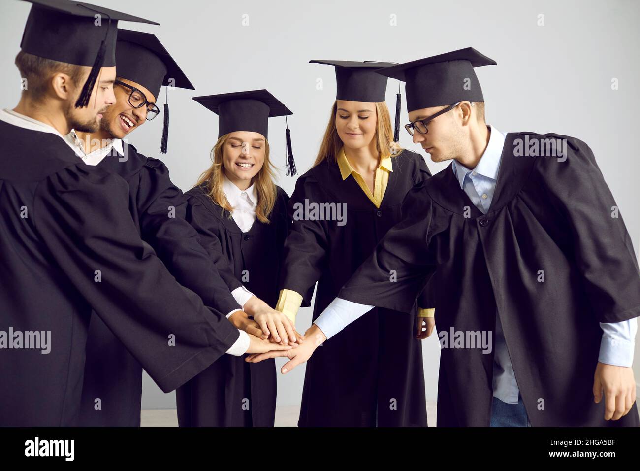 Team di studenti universitari felici in berretti e camici per celebrare la laurea Foto Stock