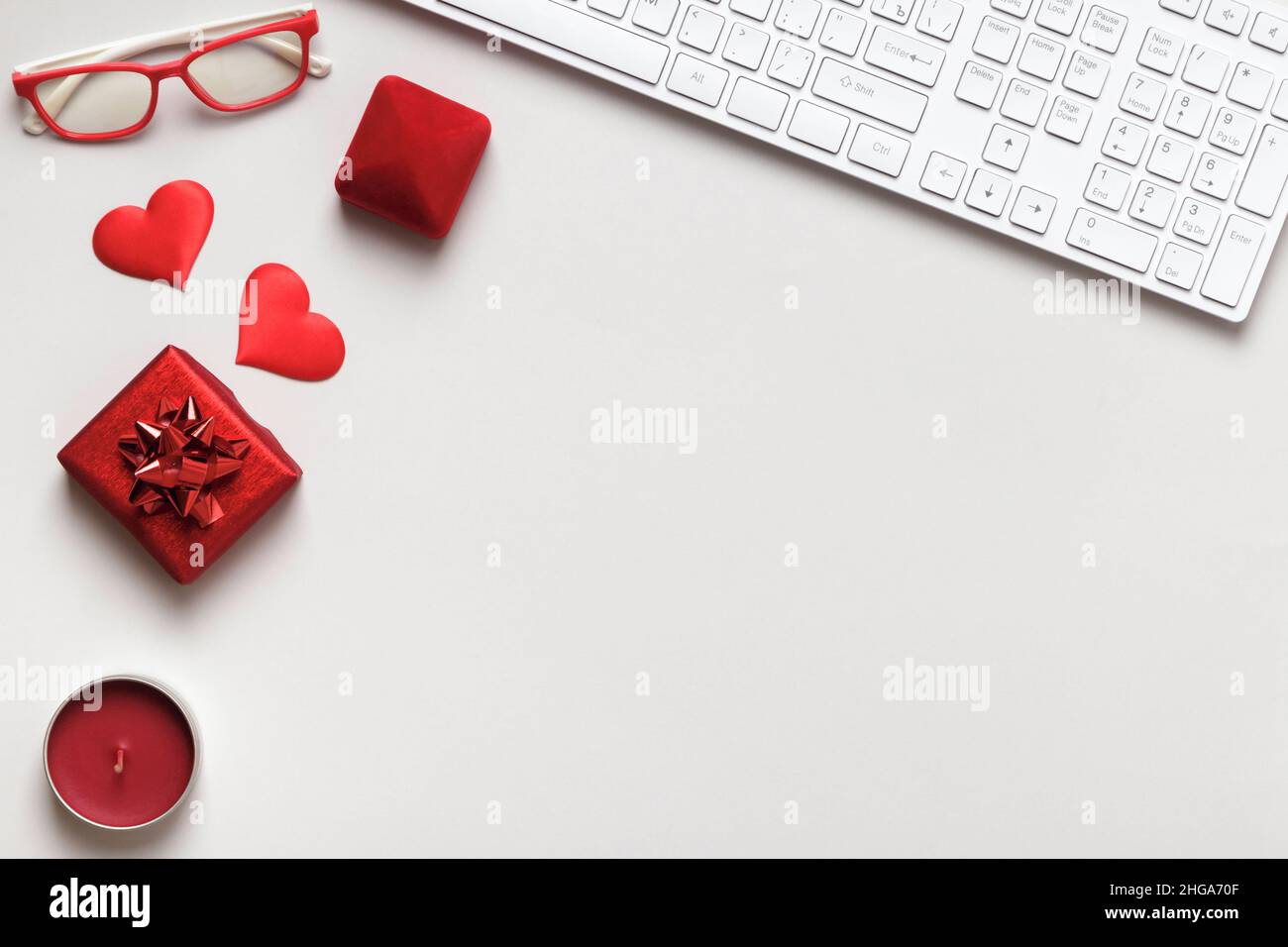 Desktop per San Valentino. Tastiera rosso cuore dono occhiali candela su tavola grigia. Vista dall'alto dello spazio di copia a disposizione piatta Foto Stock