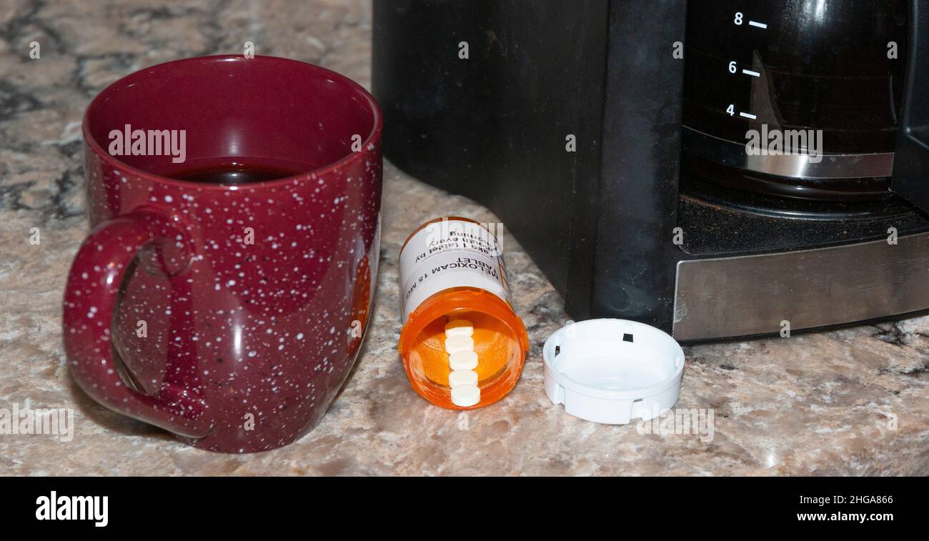 Tazza da caffè con flacone di pillole con ricetta medica e macchina da caffè su un banco in marmo. Foto Stock