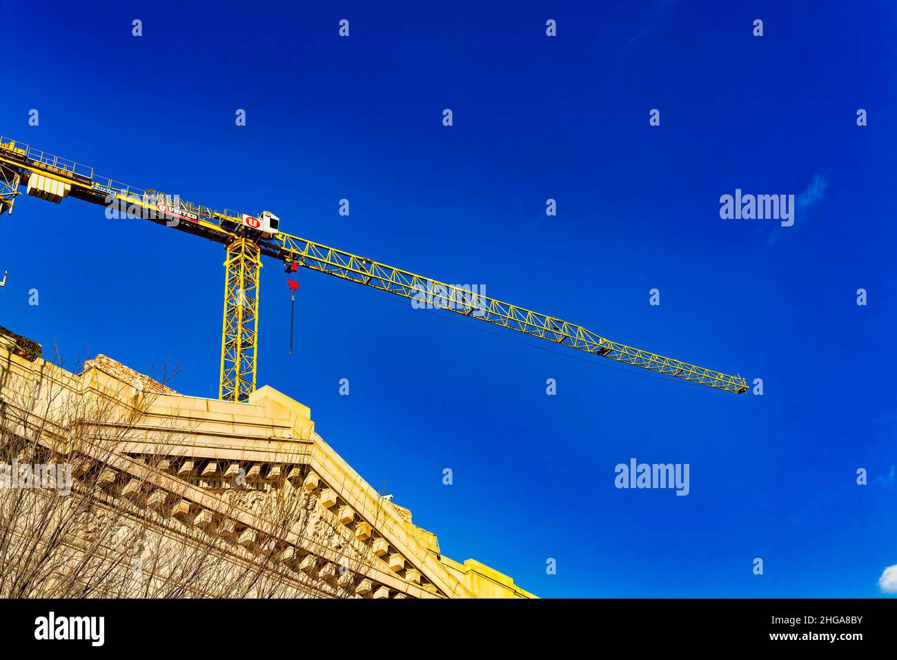 Gru in cima a un edificio del centro, contro un cielo blu brillante Foto Stock