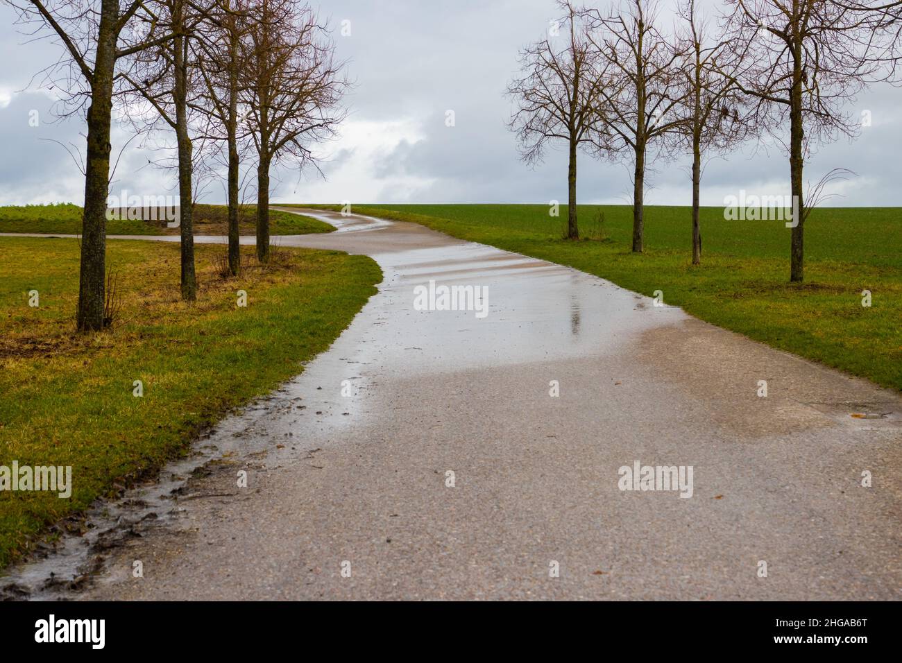 Acqua che scorre su una strada dai campi dopo piogge pesanti Foto Stock