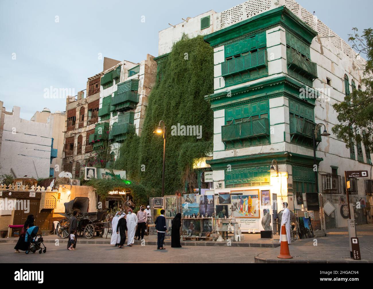 Turisti di fronte a vecchie case con mashrabiya in legno nel quartiere al-Balad, provincia Mecca, Jeddah, Arabia Saudita Foto Stock
