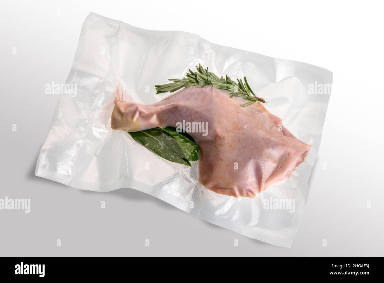 Coscia di pollo confezionata sottovuoto sigillata per la cottura sous vide  con rosmarino, foglia di alloro e salvia, isolata su bianco Foto stock -  Alamy