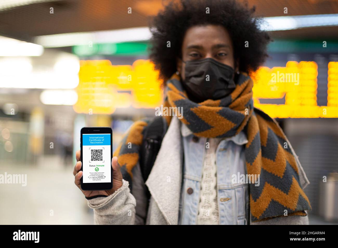 Giovane maschio afroamericano che mostra il suo certificato di vaccinazione digitale in aeroporto. Messa a fuoco selettiva. Passaporto Covid per il viaggio. Foto Stock