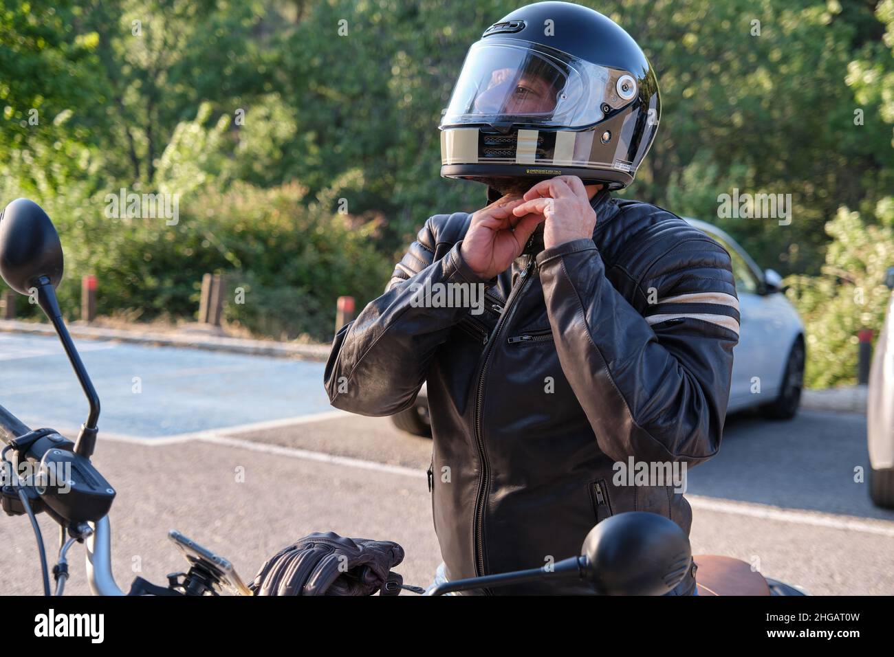 Un motociclista indossa il casco prima di andare in moto Foto Stock
