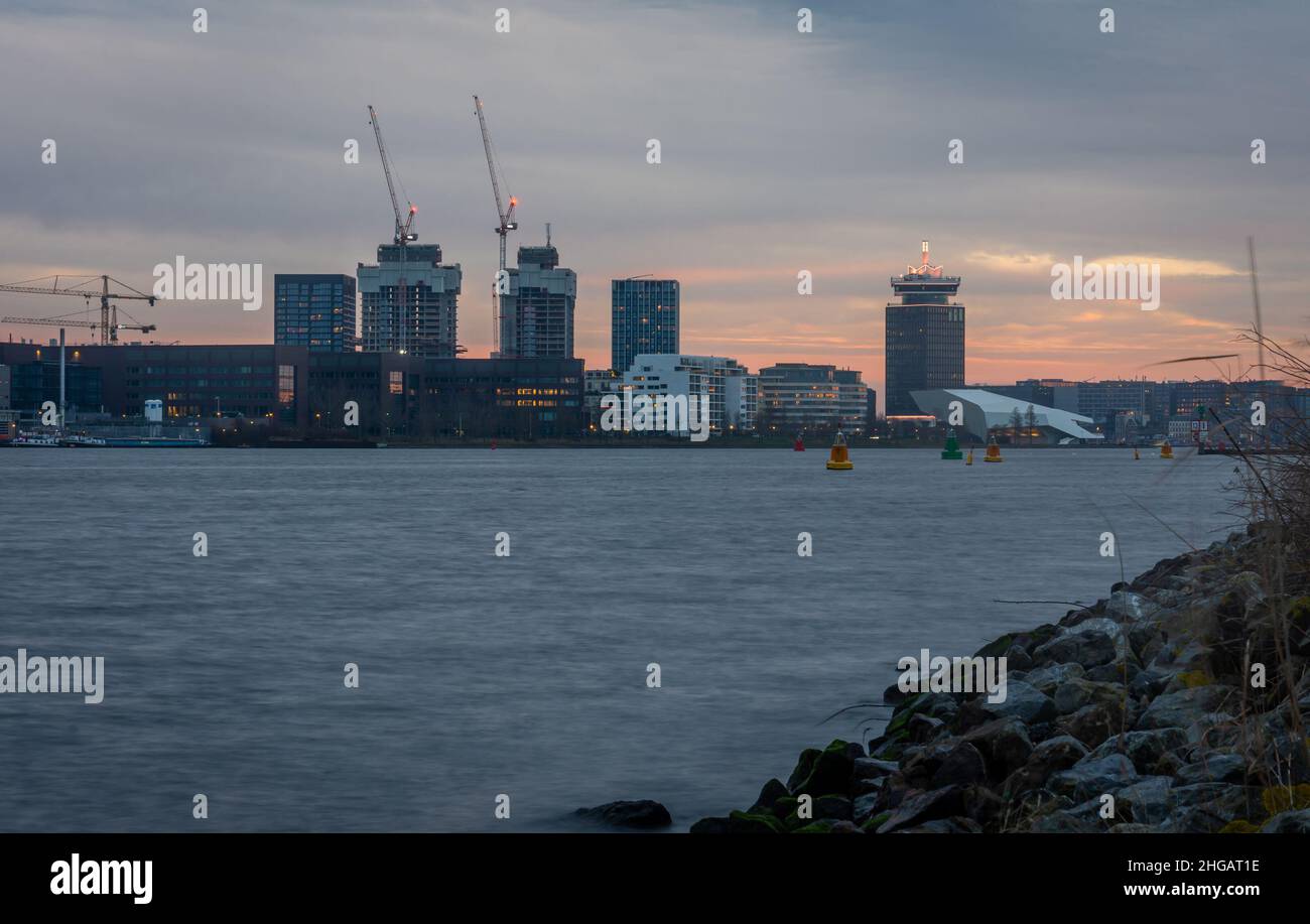 Vista sul lungomare IJ di Amsterdam e sugli edifici moderni al tramonto, vista dal porto di Houthaven Foto Stock